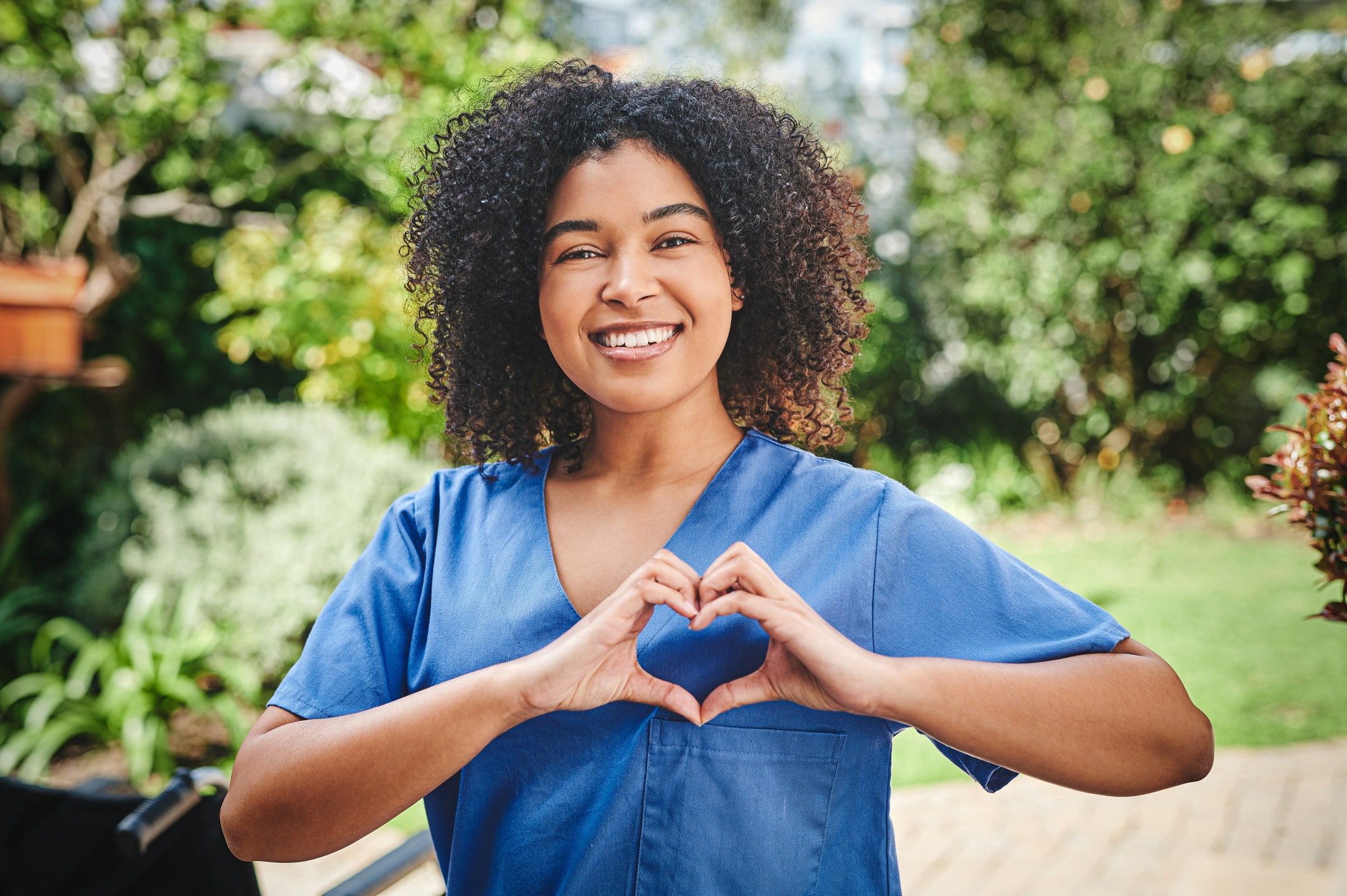 Female nurse in blue uniform standing outside and making a heart shaped gesture Female nurse in blue uniform standing outside and making a heart shaped gesture